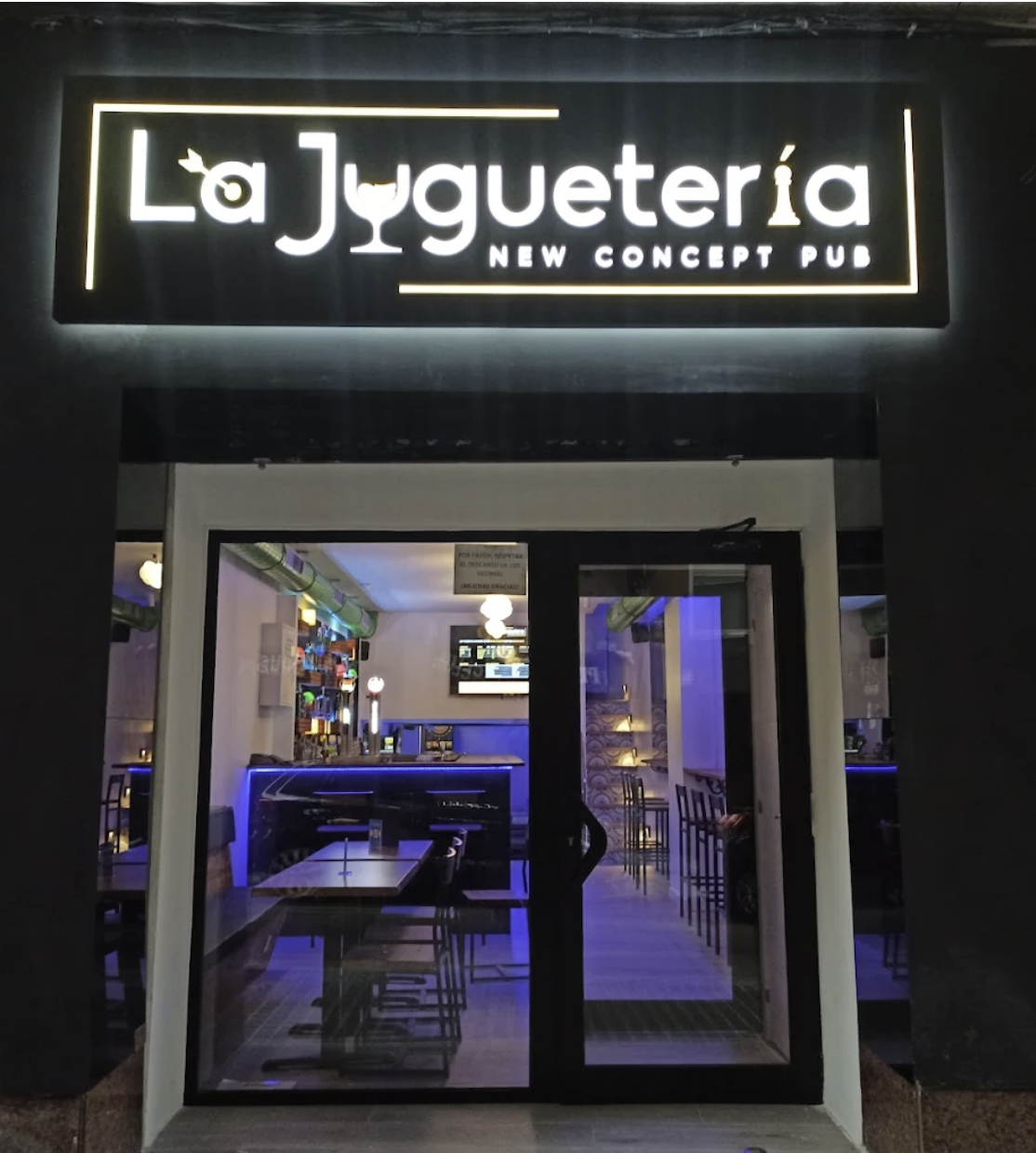 La Juguetería entrance with illuminated sign at night
